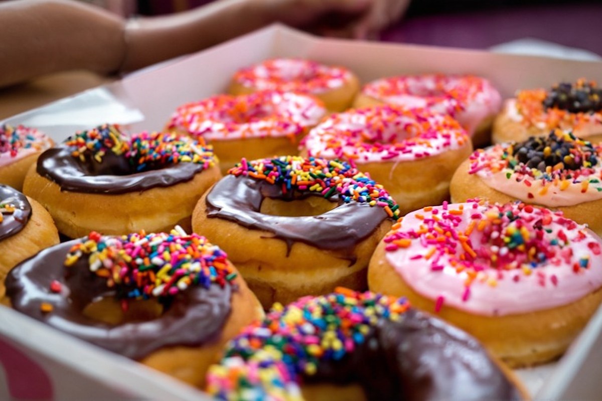 A fresh cup of coffee and a box of donuts on a cafe counter